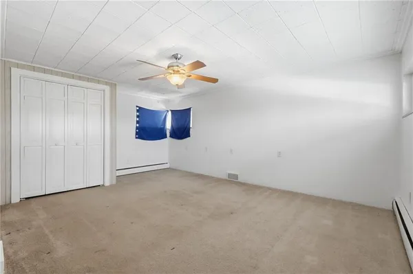 an empty room with a dining space and chandelier fan