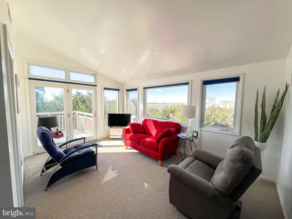 a living room with furniture floor to ceiling window and a flat screen tv