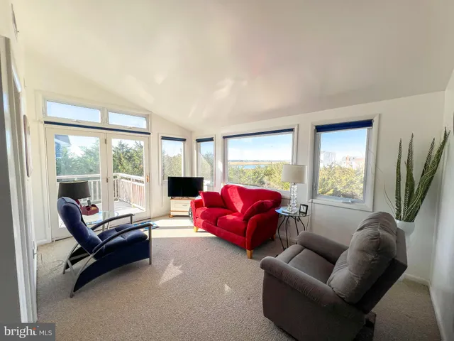 a living room with furniture floor to ceiling window and a flat screen tv
