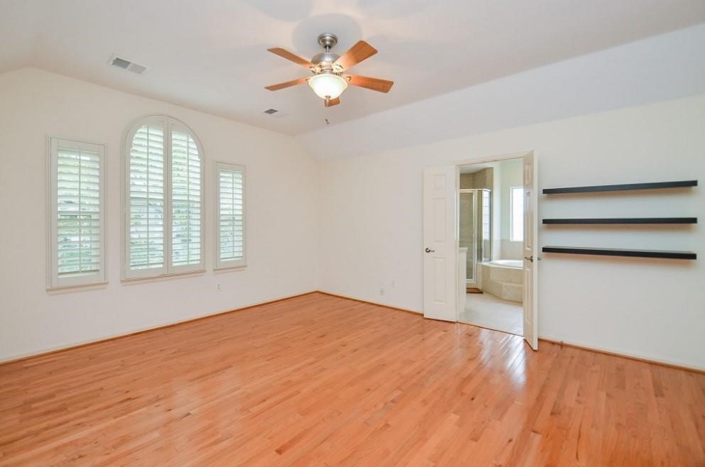 5416 Rose Street Houston, TX 77007 - Photo 13 of 19 Primary bedroom with elegant arched windows, en-suite bathroom, and stylish floating shelves.