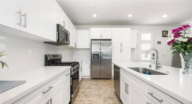 a kitchen with granite countertop a sink stainless steel appliances and cabinets