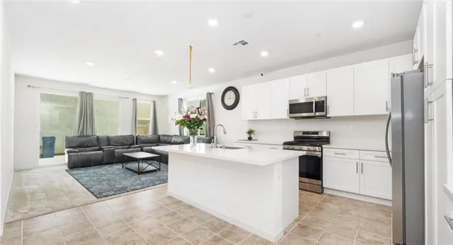 a open kitchen with stainless steel appliances granite countertop a sink dishwasher stove and refrigerator