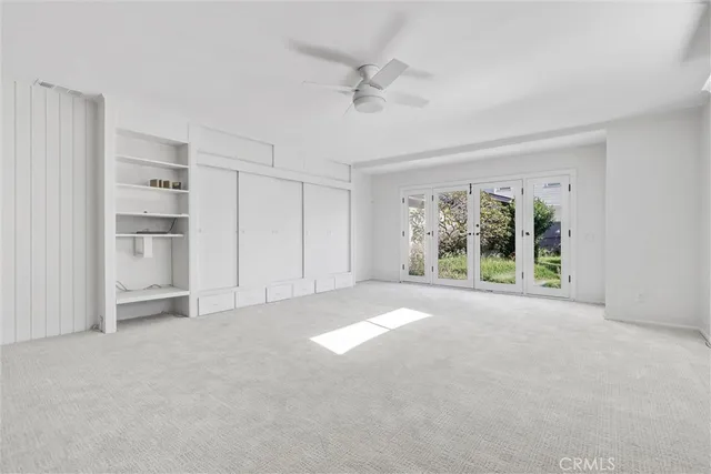 a view of an empty room with wooden floor and a ceiling fan