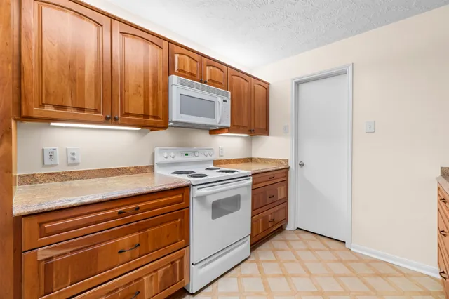 a kitchen with granite countertop a stove top oven microwave and cabinets