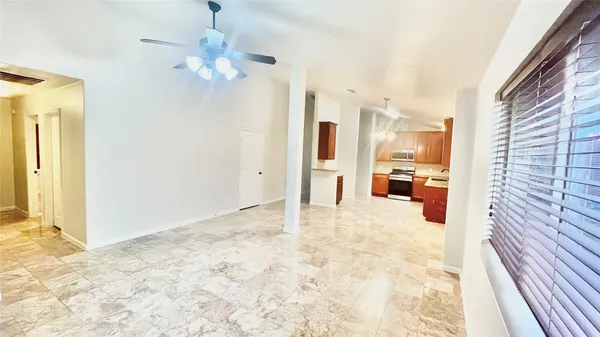 an empty room with a chandelier fan and windows