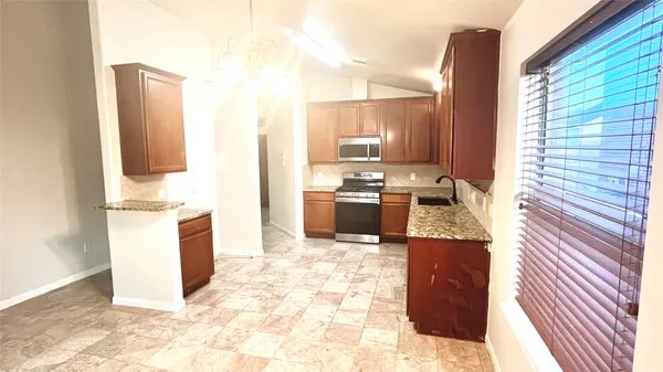 a kitchen with stainless steel appliances granite countertop a sink stove microwave and refrigerator
