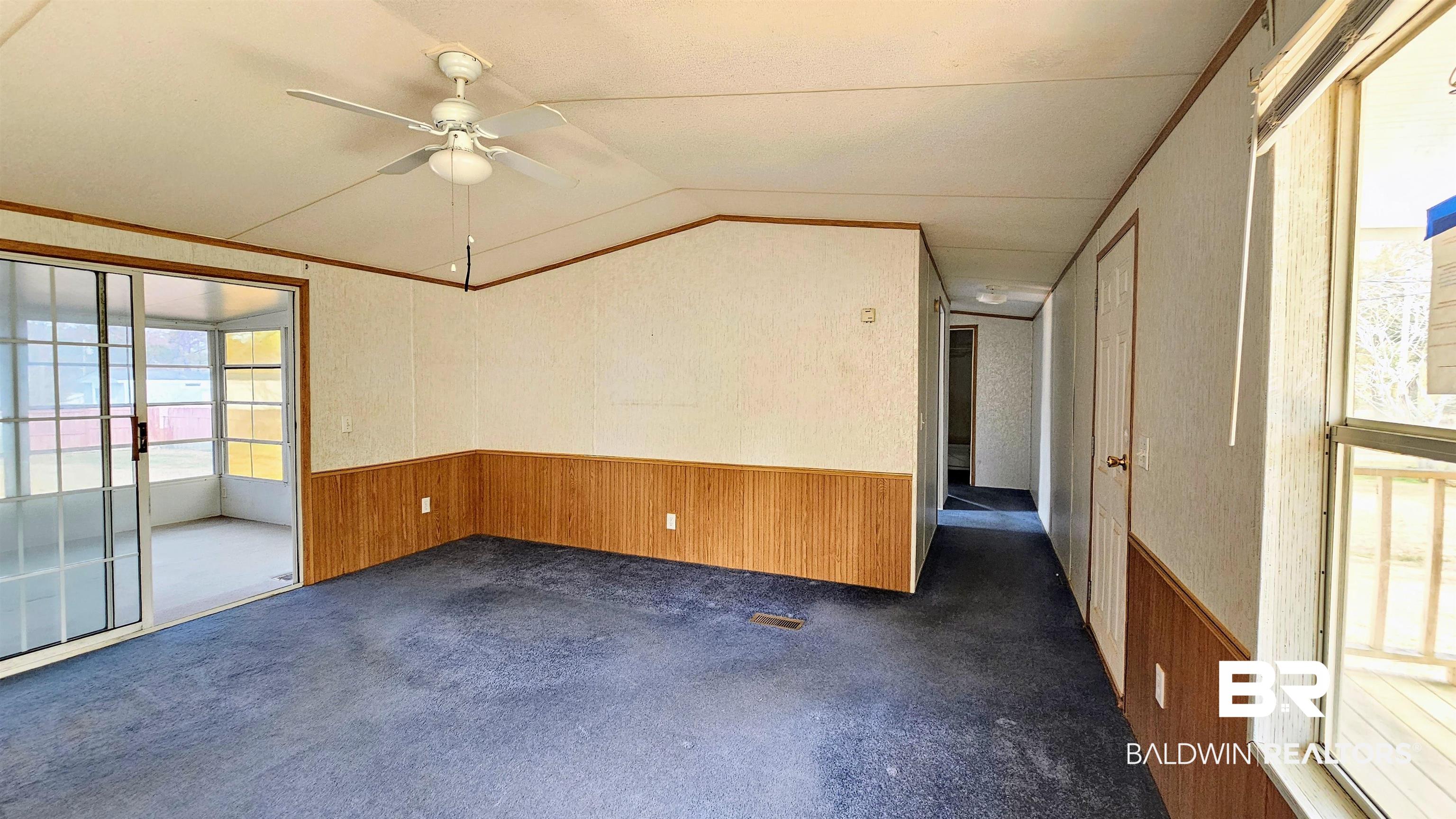 18659 Bull Springs Road Robertsdale, AL 36567 - Photo 19 of 25 Carpeted empty room with vaulted ceiling, crown molding, ceiling fan, and wooden walls