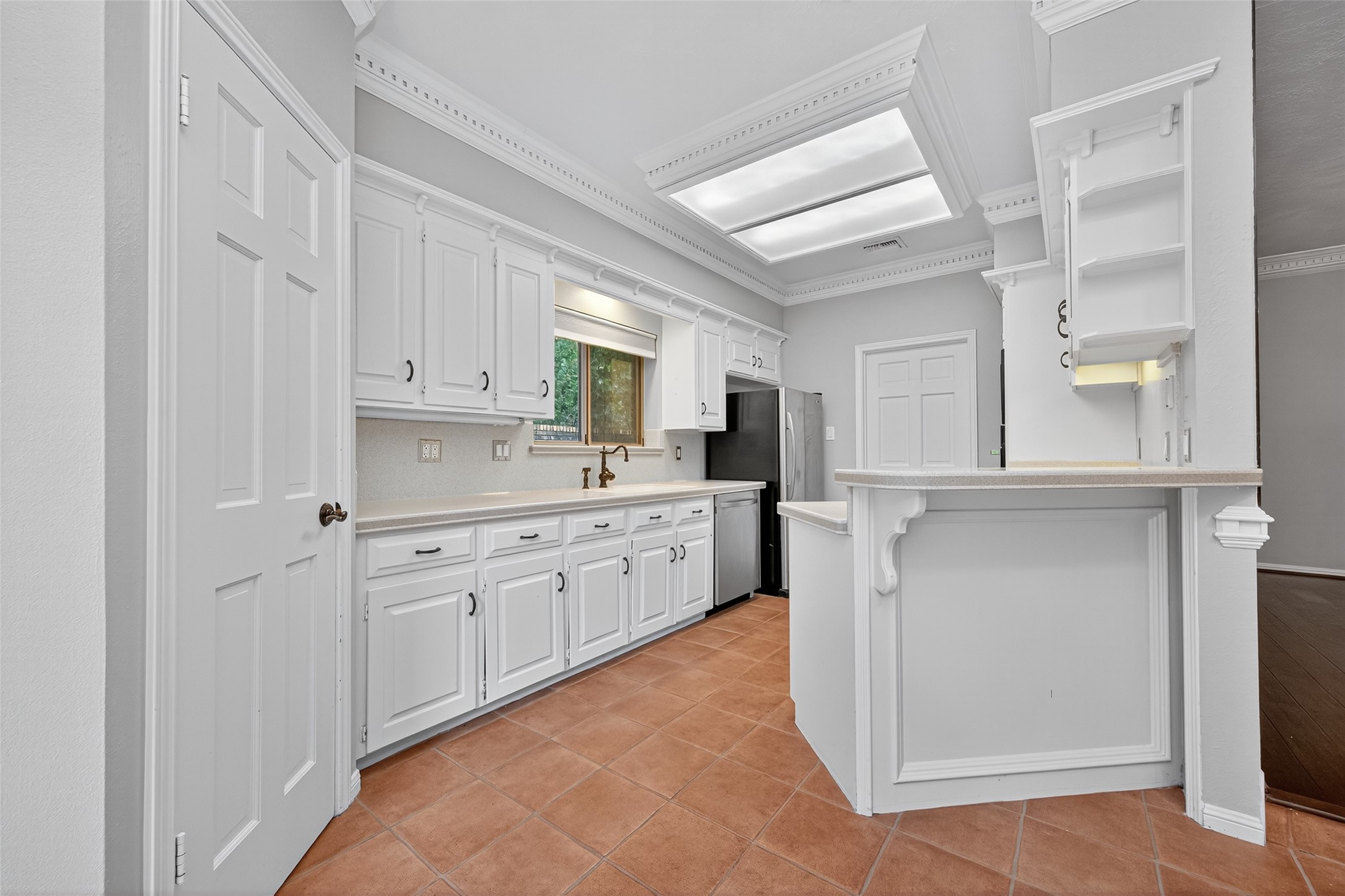 901 Longmire Road, Unit 13 Conroe, TX 77304 - Photo 20 of 46 Bright, spacious kitchen with white cabinetry, stainless steel appliances, and terracotta tile flooring. Features a breakfast bar and ample counter space, perfect for cooking and entertaining.