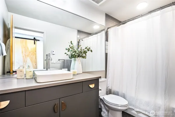 a bathroom with a granite countertop sink toilet and mirror