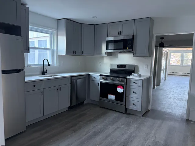 a kitchen with stainless steel appliances a stove a sink dishwasher a refrigerator and a microwave