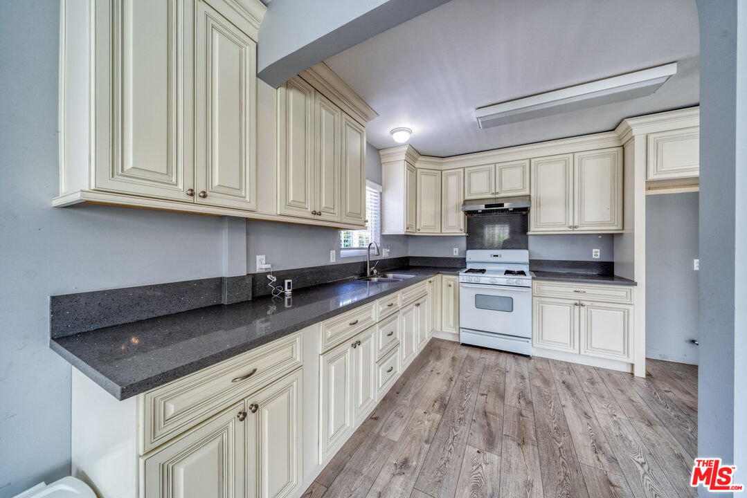 117 South Virgil Avenue Los Angeles, CA 90004 - Photo 4 of 33 a kitchen with granite countertop white cabinets and white appliances