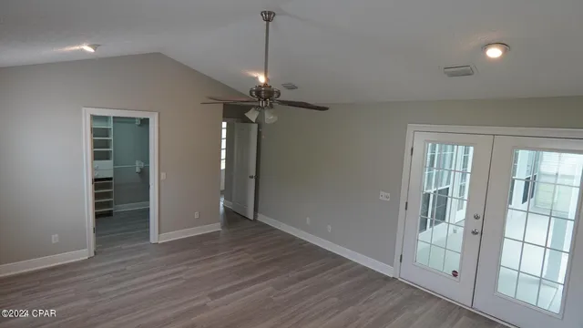 an empty room with wooden floor fan and windows