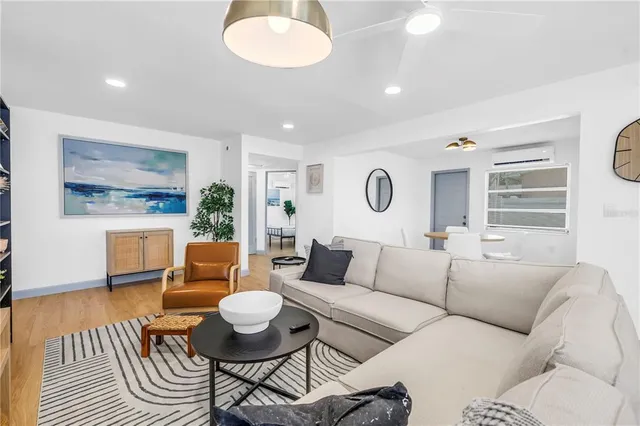 a living room with furniture kitchen view and a wooden floor