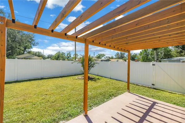 a view of backyard with large trees and wooden fence