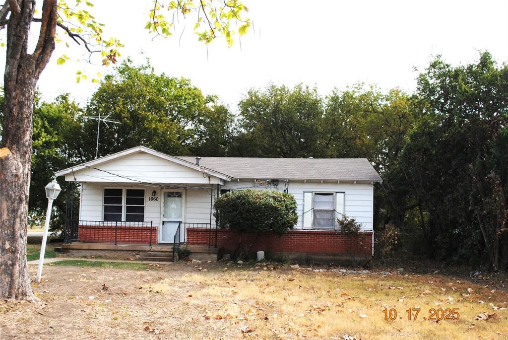 Bungalow-style house with a porch. Metal siding with brick trim.