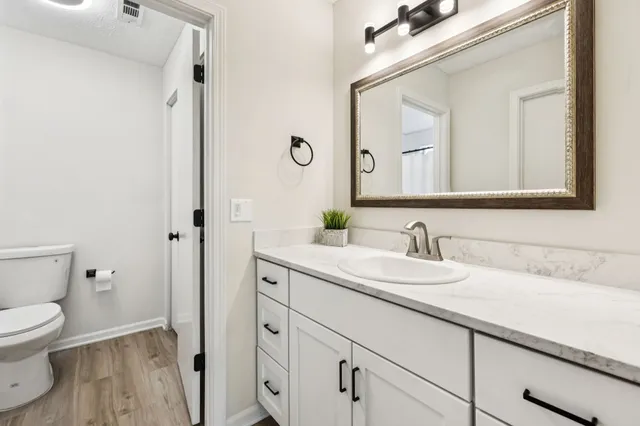 a bathroom with a granite countertop sink mirror and toilet