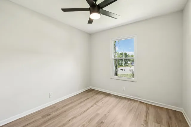 an empty room with a window and a fan