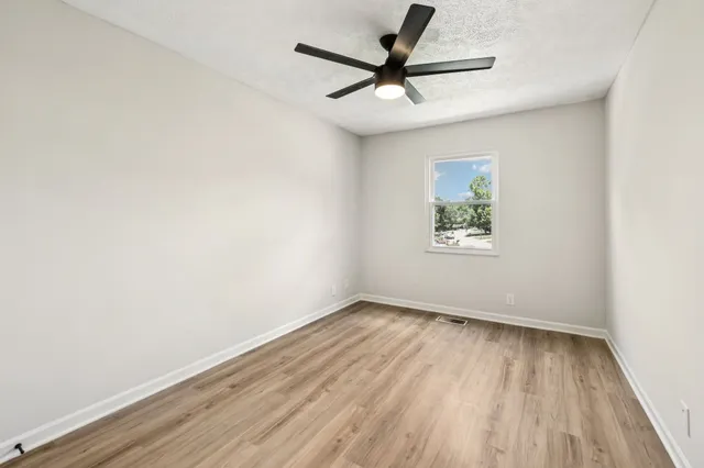 an empty room with wooden floor and windows