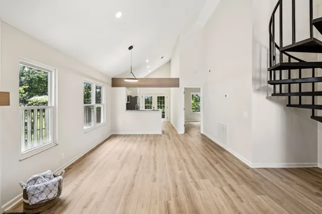 a view of an empty room with a window and wooden floor