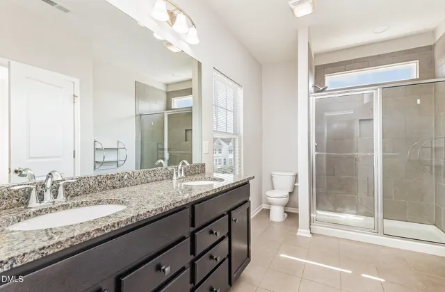 a bathroom with a granite countertop sink a toilet and a large mirror