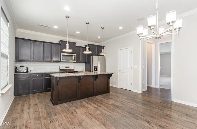 a large kitchen with stainless steel appliances granite countertop a lot of counter space and wooden floors