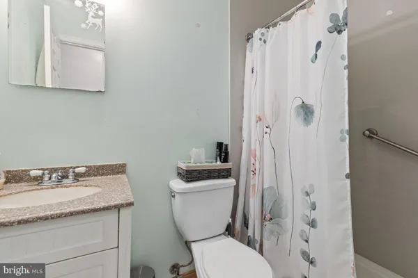 a bathroom with a granite countertop toilet a sink and a mirror