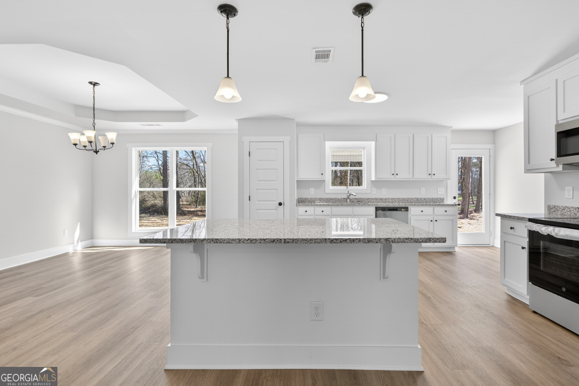 302 Mockingbird Lane, Unit 25 Winder, GA 30680 - Photo 16 of 38 a large kitchen with granite countertop a stove a sink a window and wooden floor