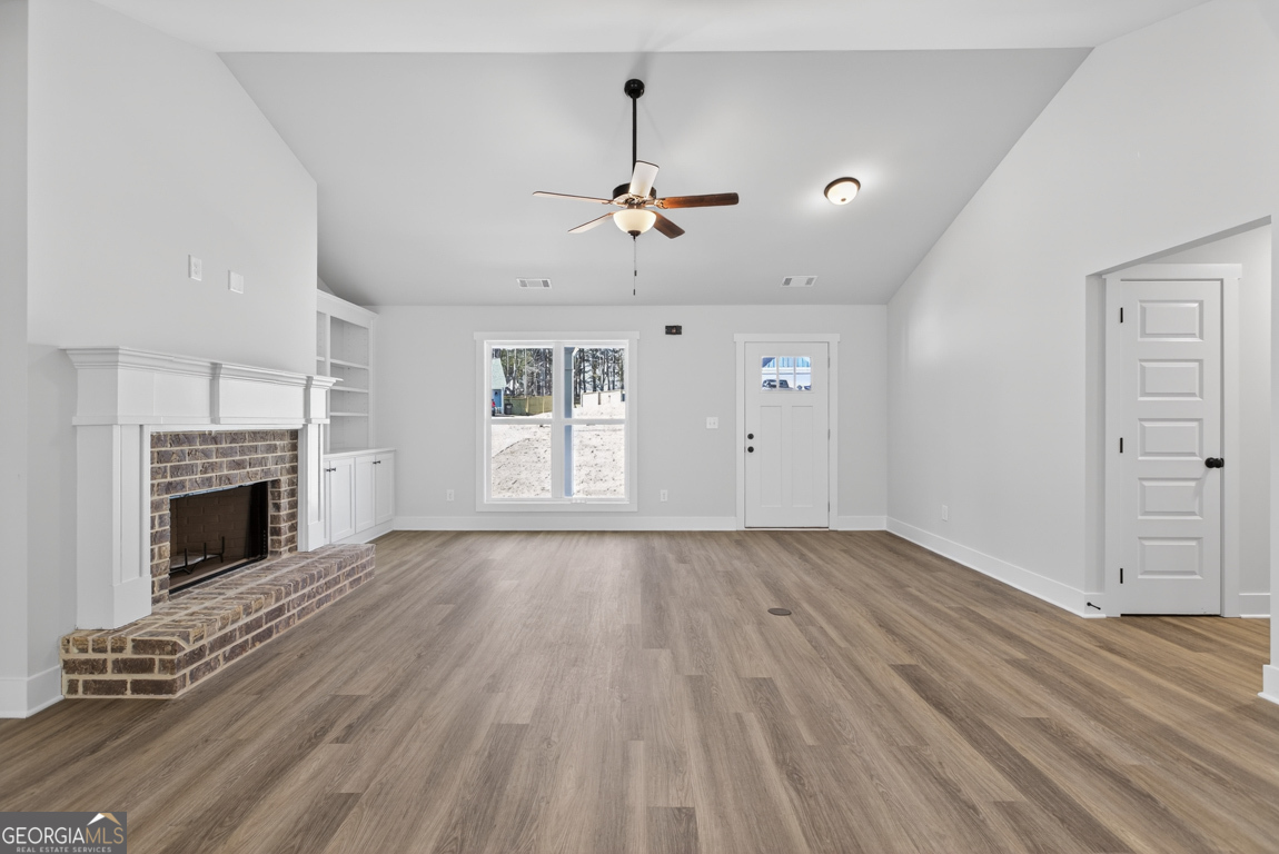 302 Mockingbird Lane, Unit 25 Winder, GA 30680 - Photo 7 of 38 an empty room with windows fireplace and wooden floor