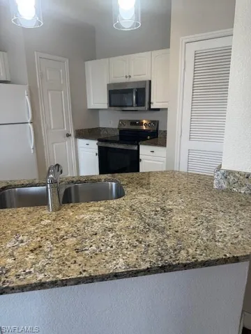 a kitchen with kitchen island granite countertop a sink a stove and a microwave