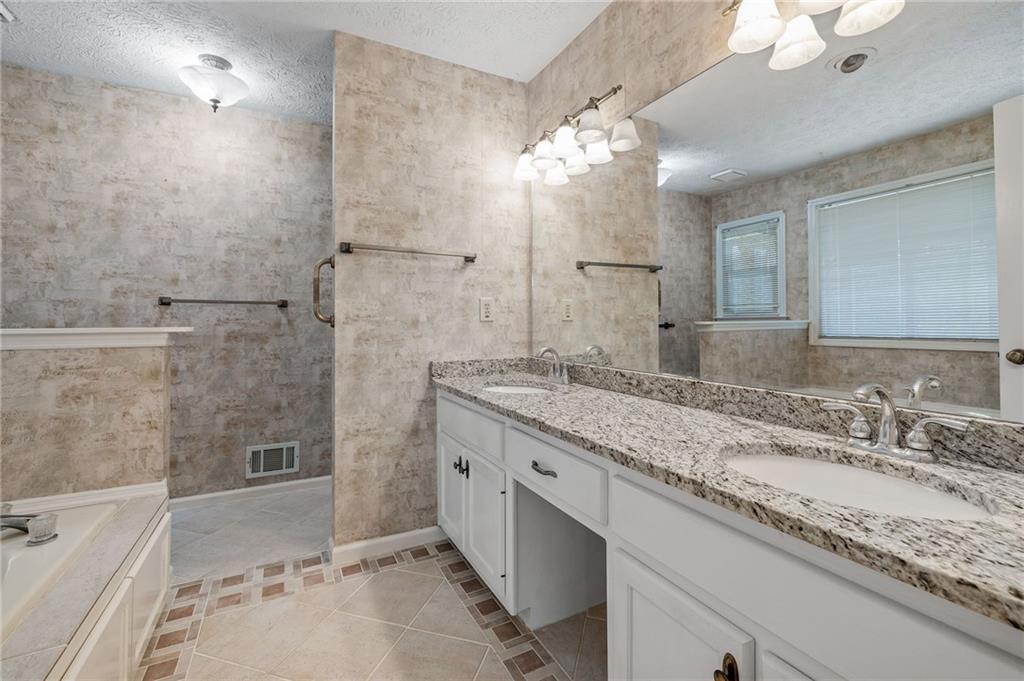 3374 Floral Court Suwanee, GA 30024 - Photo 20 of 54 a bathroom with a granite countertop sink a large mirror and a bathtub