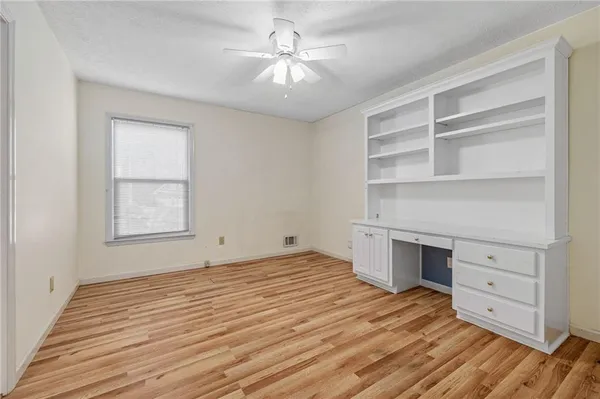 an empty room with windows and ceiling fan