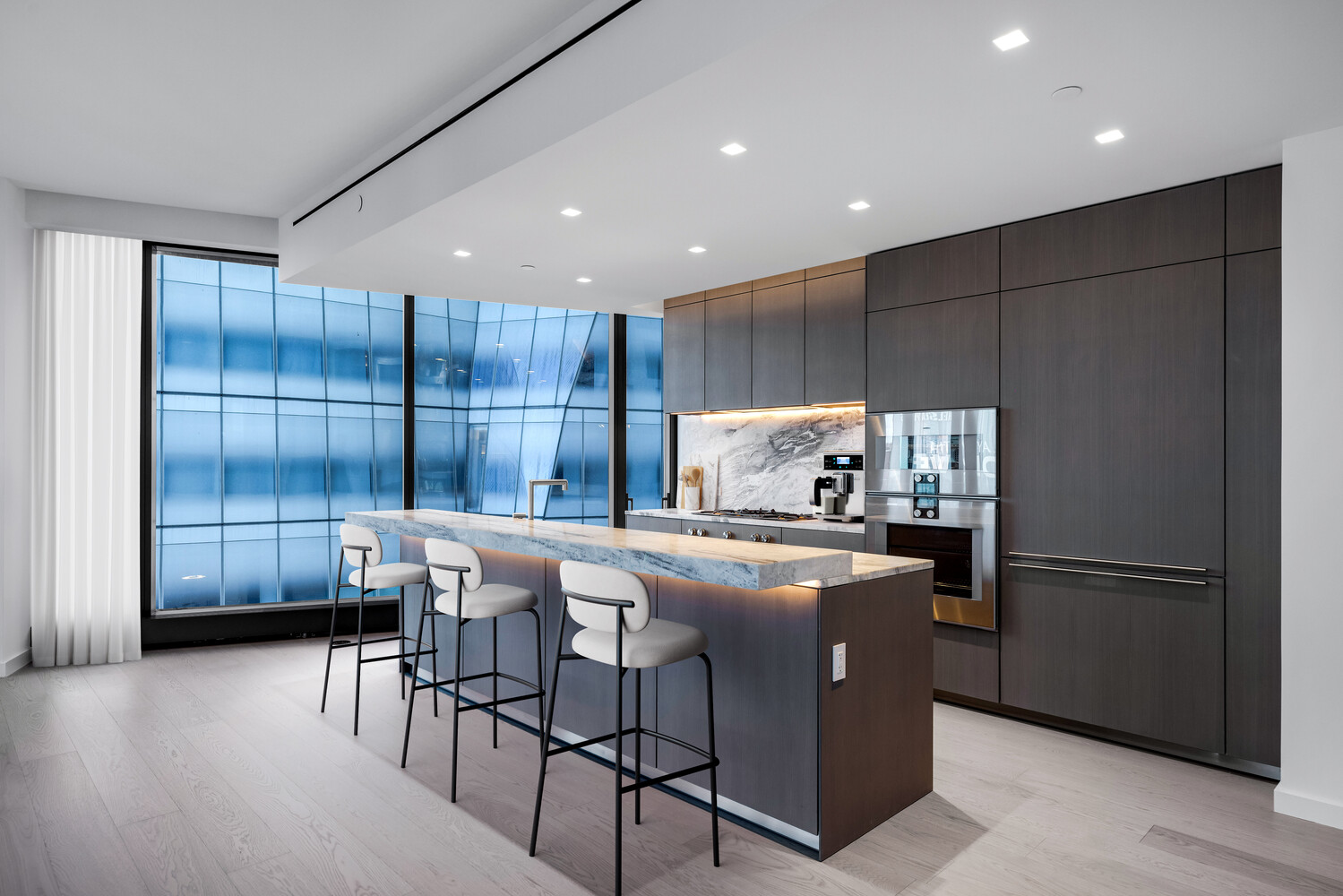 500 West 18th Street, Unit 5C Manhattan, NY 10011 - Photo 3 of 9 a kitchen with kitchen island granite countertop wooden cabinets and stainless steel appliances