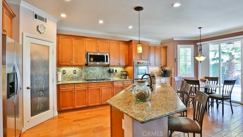 30240 Lamplighter Lane Menifee, CA 92584 - Photo 5 of 20 a kitchen with stainless steel appliances granite countertop sink refrigerator dining table and chairs