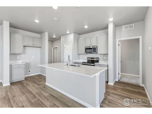 a large white kitchen with cabinets and wooden floor