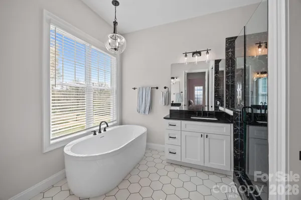 a spacious bathroom with a sink a mirror a bathtub and a shower