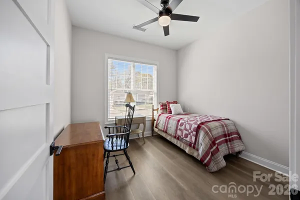 a bedroom with a bed chair and wooden floor
