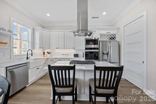 a kitchen with stainless steel appliances kitchen island granite countertop a dining table chairs and a refrigerator