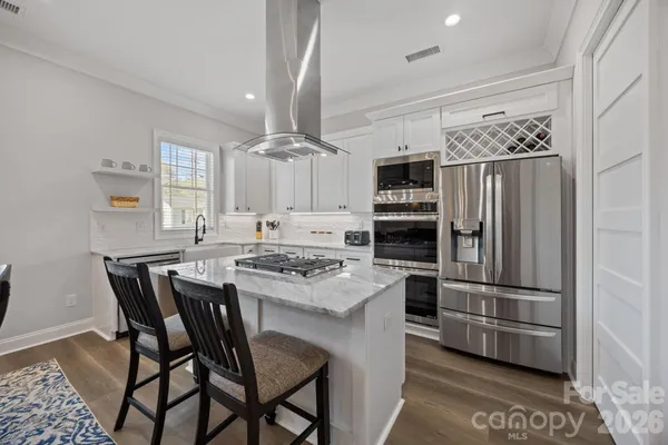 a kitchen with stainless steel appliances a dining table and chairs