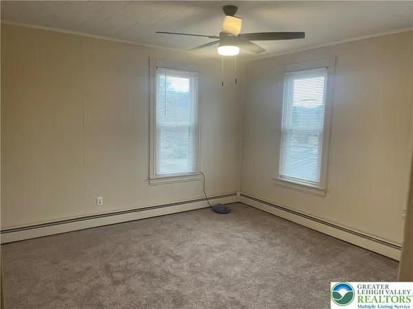 an empty room with windows and fan