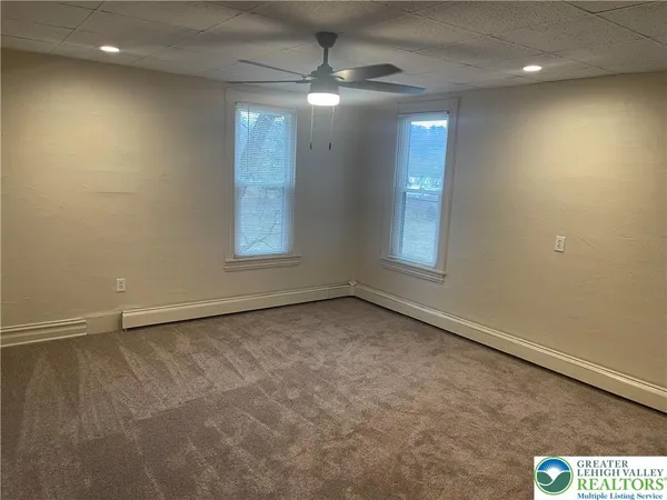 an empty room with windows and fan