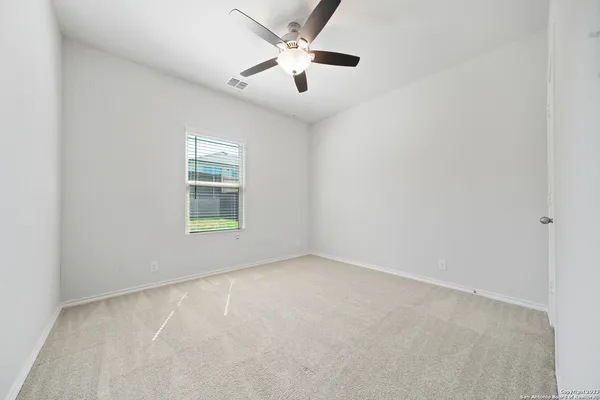 an empty room with windows and fan