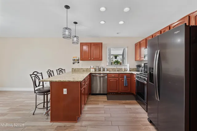 a kitchen with stainless steel appliances granite countertop a refrigerator a stove a sink dishwasher a dining table and chairs with wooden floor