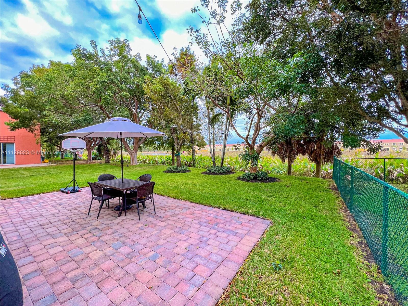 1399 Southeast 20th Road Homestead, FL 33035 - Photo 28 of 50 a view of a yard with a table and chairs under an umbrella