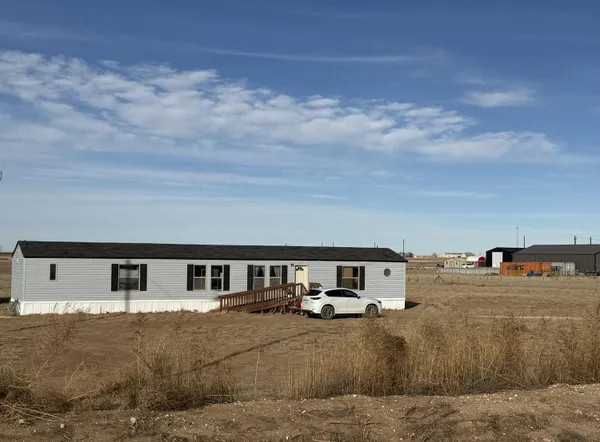 a front view of a house with large trees