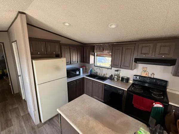 a kitchen with a refrigerator a stove top oven a sink and dishwasher with wooden floor