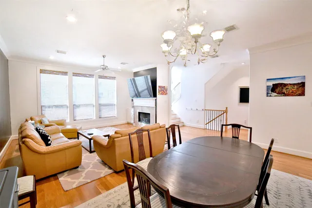 a view of a dining room with furniture a chandelier and large windows