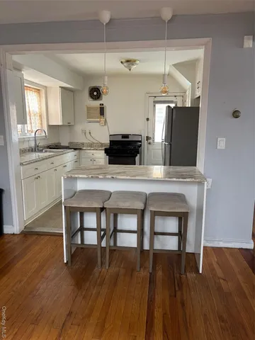a kitchen with kitchen island a dining table chairs cabinets and wooden floor
