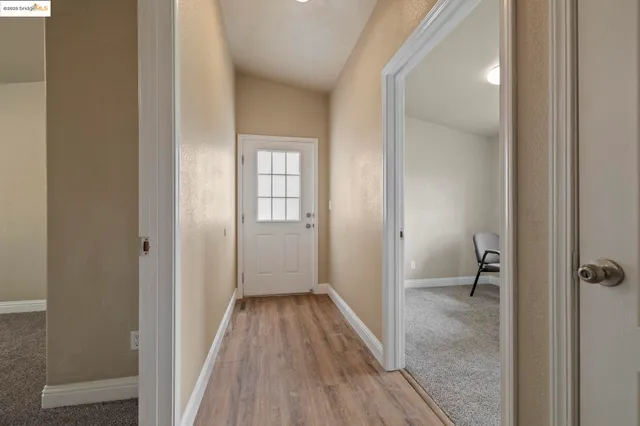 a view of a hallway with a room space and wooden floor