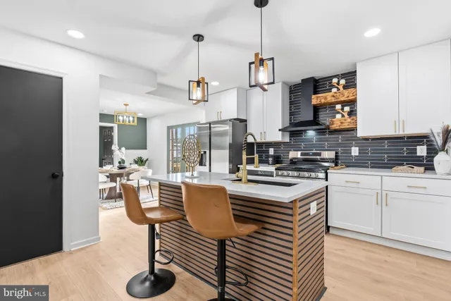 a kitchen with stainless steel appliances granite countertop a stove a sink a refrigerator and a dining table with wooden floor