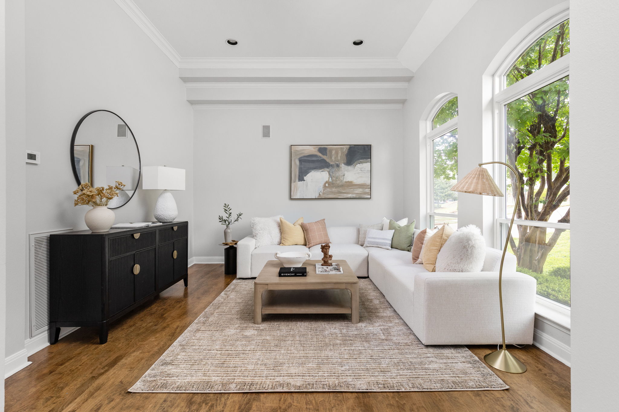 Bright living space featuring wood-finish flooring, a coffered ceiling with recessed lighting, and large arched windows